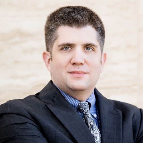 Abogado Bryan Fagan, especializado en derecho familiar, con traje oscuro y corbata, posando con fondo neutro, representando la dedicación a la protección de derechos parentales en casos de CPS en Texas.