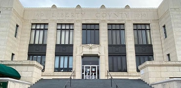 Edificio del Tribunal del Condado de Liberty, fachada con inscripciones, escaleras de acceso, y ventanas grandes, representando el sistema judicial en Liberty County, Texas.