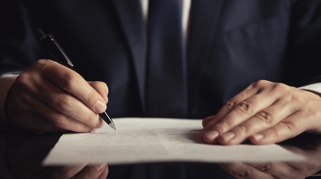 Abogado especializado en sucesiones firmando documentos legales sobre planificación patrimonial y administración de herencias.